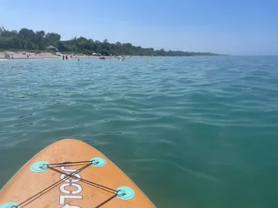 The nose of a paddleboard gliding over clear turquoise water toward a beach