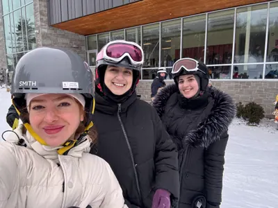 Three friends in helmets and goggles at the bottom of a ski hill